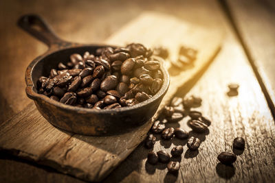 Aromatic coffee beans in an old rustic pot on a wooden table setting