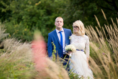 Portrait of smiling newlywed couple standing at grassy field