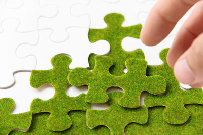 Cropped image of hand holding green puzzle piece
