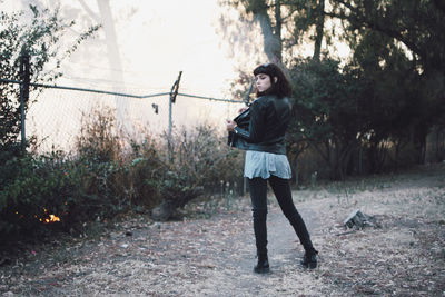 Full length portrait of young woman standing on land