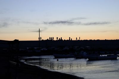 Silhouette boats moored on sea against sky during sunset