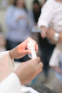 Cropped hands of priest igniting candle at church