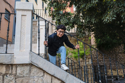 Young transgender person smiling while posing standing on stairs outdoors.