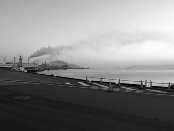 View of factory by sea against sky