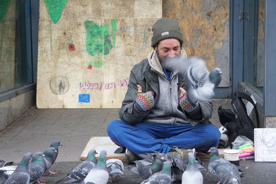 Side view of young man sitting on street