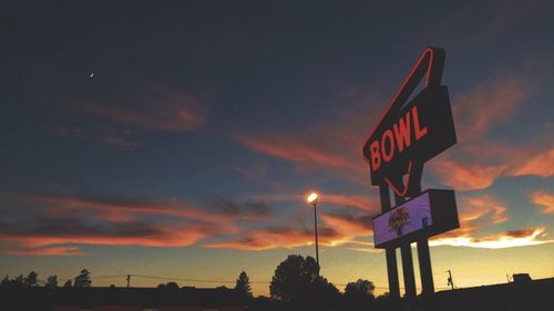 Low angle view of road sign against sky during sunset