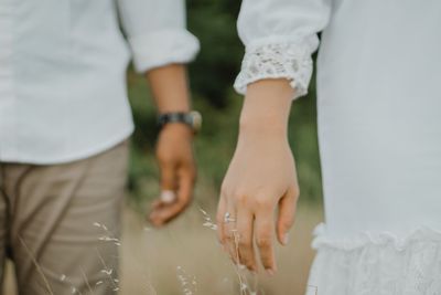 Midsection of couple holding hands