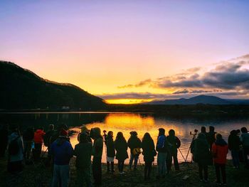 People looking at view of mountains during sunset