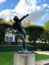 Statue by fountain in park against sky