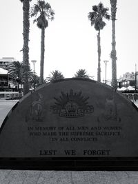 Information sign on palm tree against sky