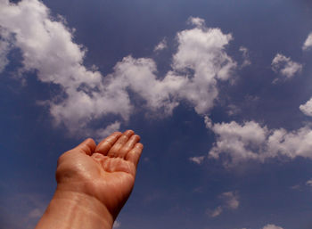 Low angle view of person hand against sky