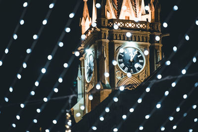 Low angle view of illuminated clock hanging on ceiling