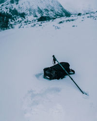 High angle view of backpack and hiking pole on snowy land