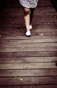 Low section of woman walking on boardwalk