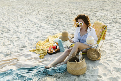 Smiling woman wearing flower sunglasses using smart phone at beach