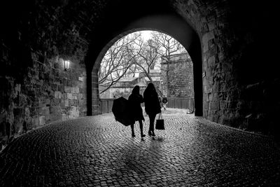 Rear view of people walking on footpath in tunnel