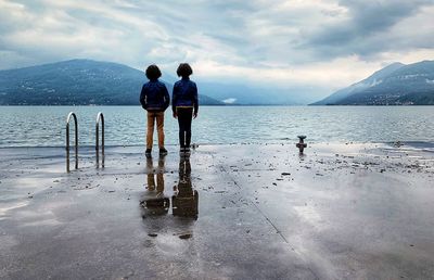 Rear view of siblings standing at promenade against sky