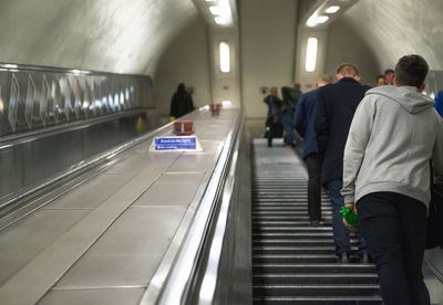 Rear view of people traveling on escalator