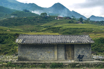 House on field against mountains