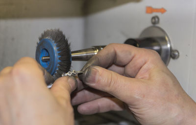 Close-up of hands polishing metal in factory