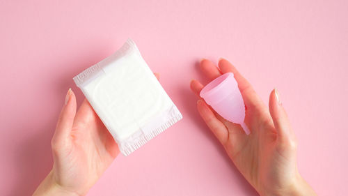 Close-up of hand holding pink over white background