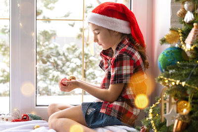 Young woman holding christmas tree at home