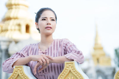 Young woman looking away while standing by railing