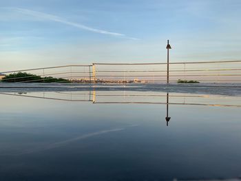 Reflection of bridge on water against sky