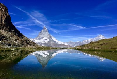 Scenic view of lake and mountains against blue sky