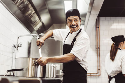 Happy male chef looking away while preparing food in kitchen