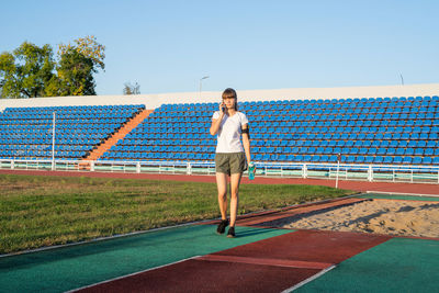 Full length of young woman standing against blue sky