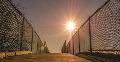 Sun shining through fence during sunset