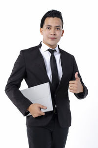 Portrait of young man standing against white background