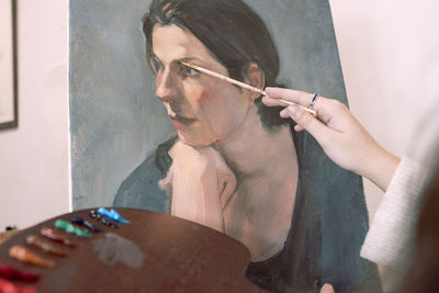 Female artist painting woman on canvas at art studio