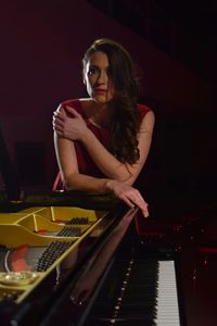 Beautiful musician leaning on piano in theater