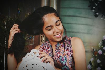 Close-up smiling young woman with eyes closed holding hair at home