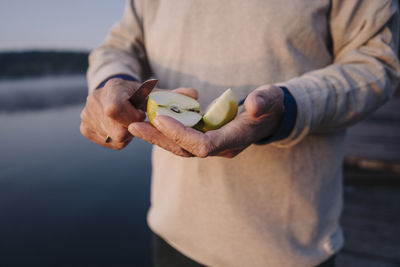 Man holding slice of apple while standing outdoors