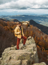 Happy traveler is standing on rock and enjoying the journey. scenic landscape with view to a forest