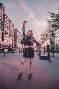 Full length portrait of woman standing on street in city