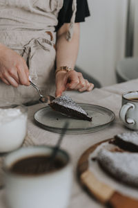 Woman putting piece of freshly baked chocolate cake on plate