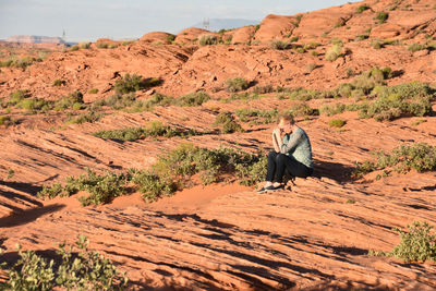 Rear view of man sitting on rock