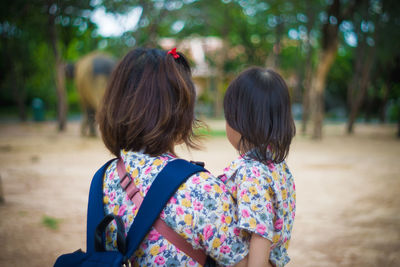 Rear view of women standing against trees