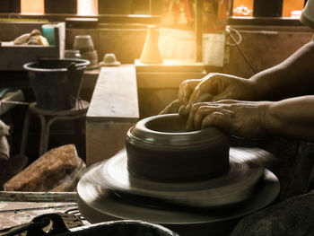 Cropped hands of potter making pot on wheel at workshop