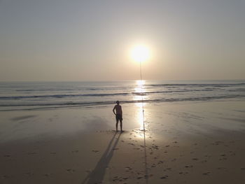 Silhouette person on beach against sky during sunset