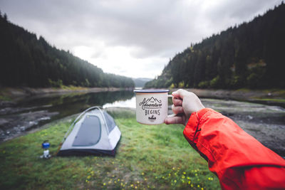 Cropped image of man holding mug against sky