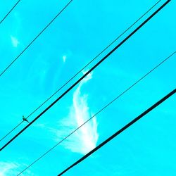 Low angle view of power cables against blue sky