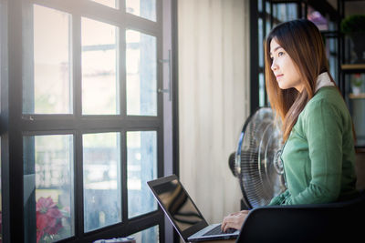 Young woman looking through window