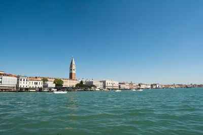 View of buildings in city against clear blue sky