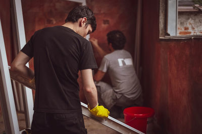 Two young caucasian brunette men wash window frames on the floor