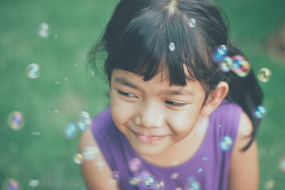 Close-up of smiling girl with bubbles at public park